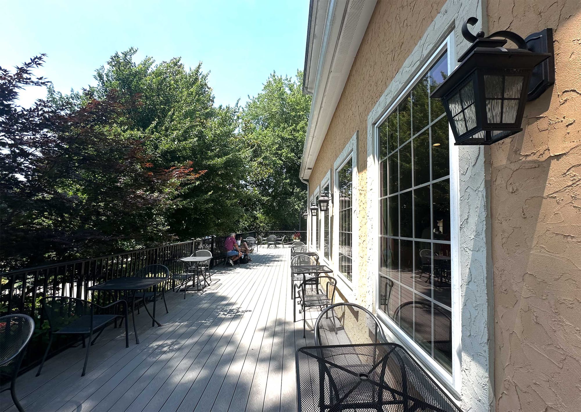Outdoor shaded patio with tables and chairs.