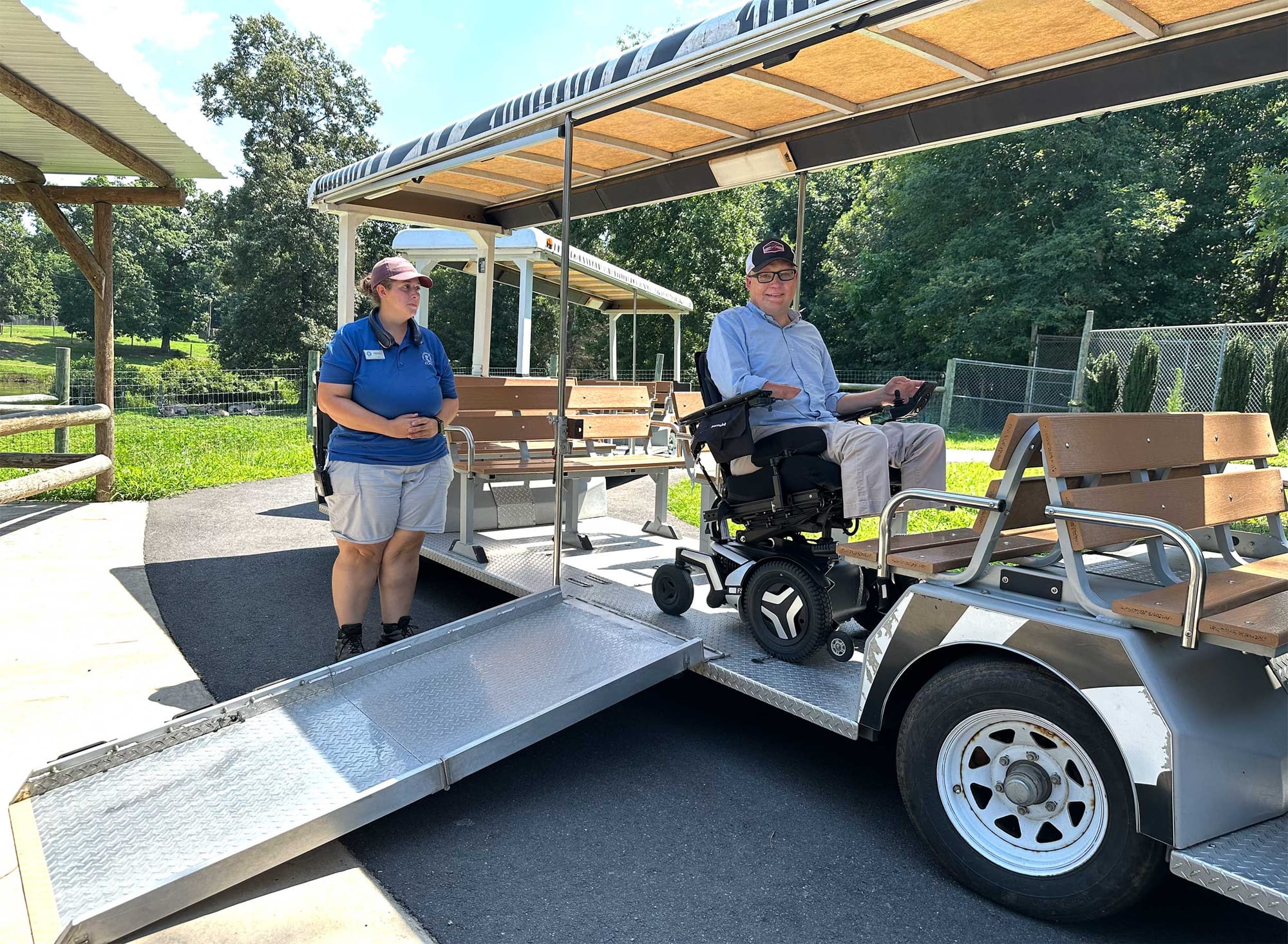 John seated in his wheelchair onboard a train vehicle with ramp.