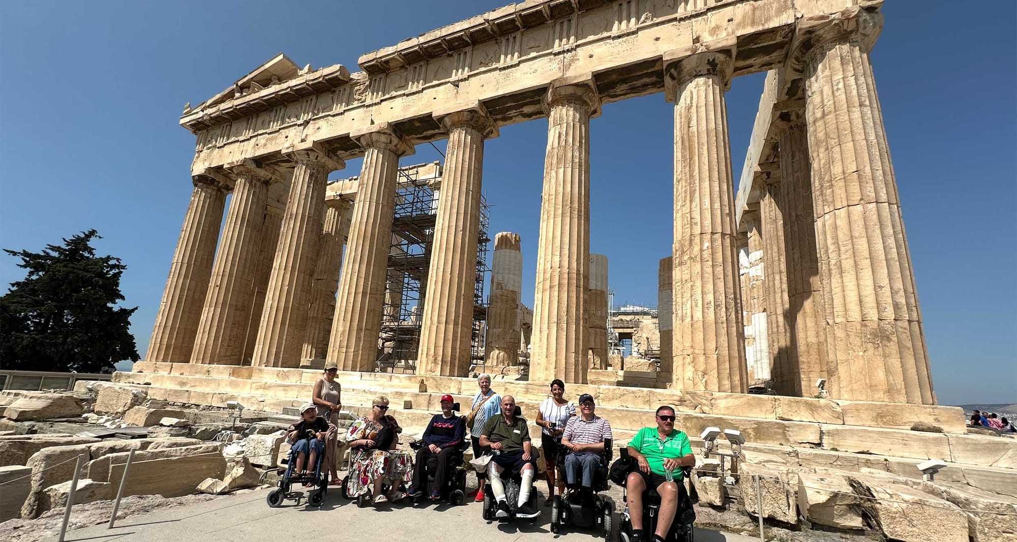 Group of wheelchair users atop the Acropolis in Athens, Greece, in front of the Pantheon.