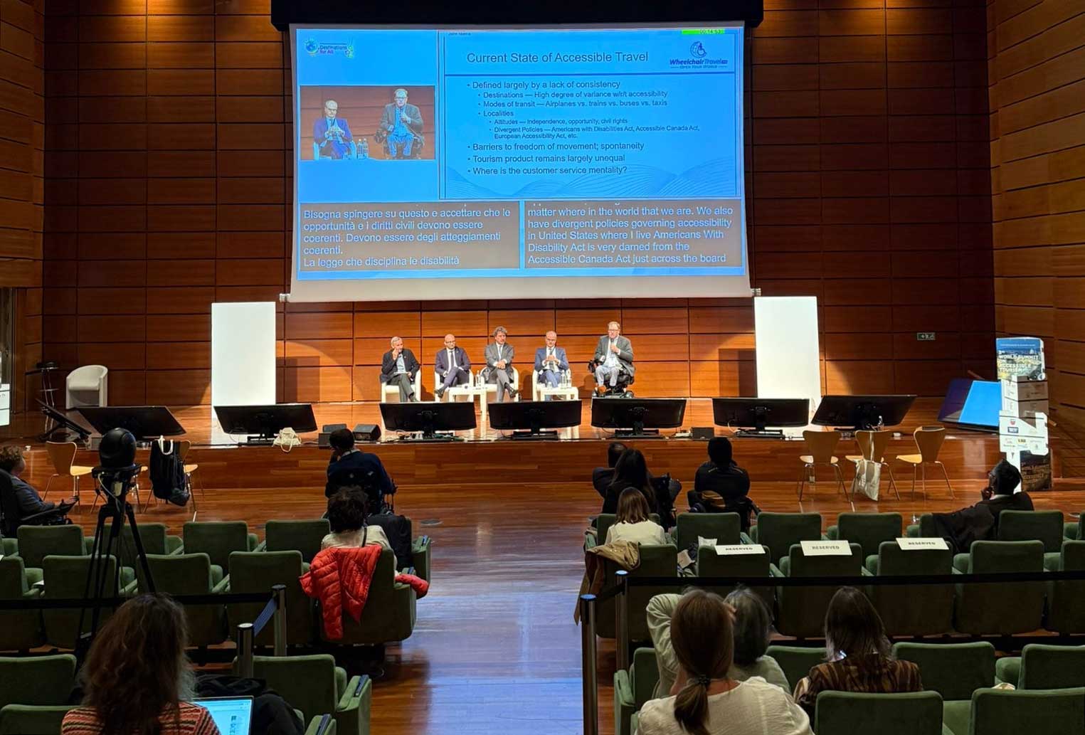 John speaking as part of a panel onstage in a large auditorium.