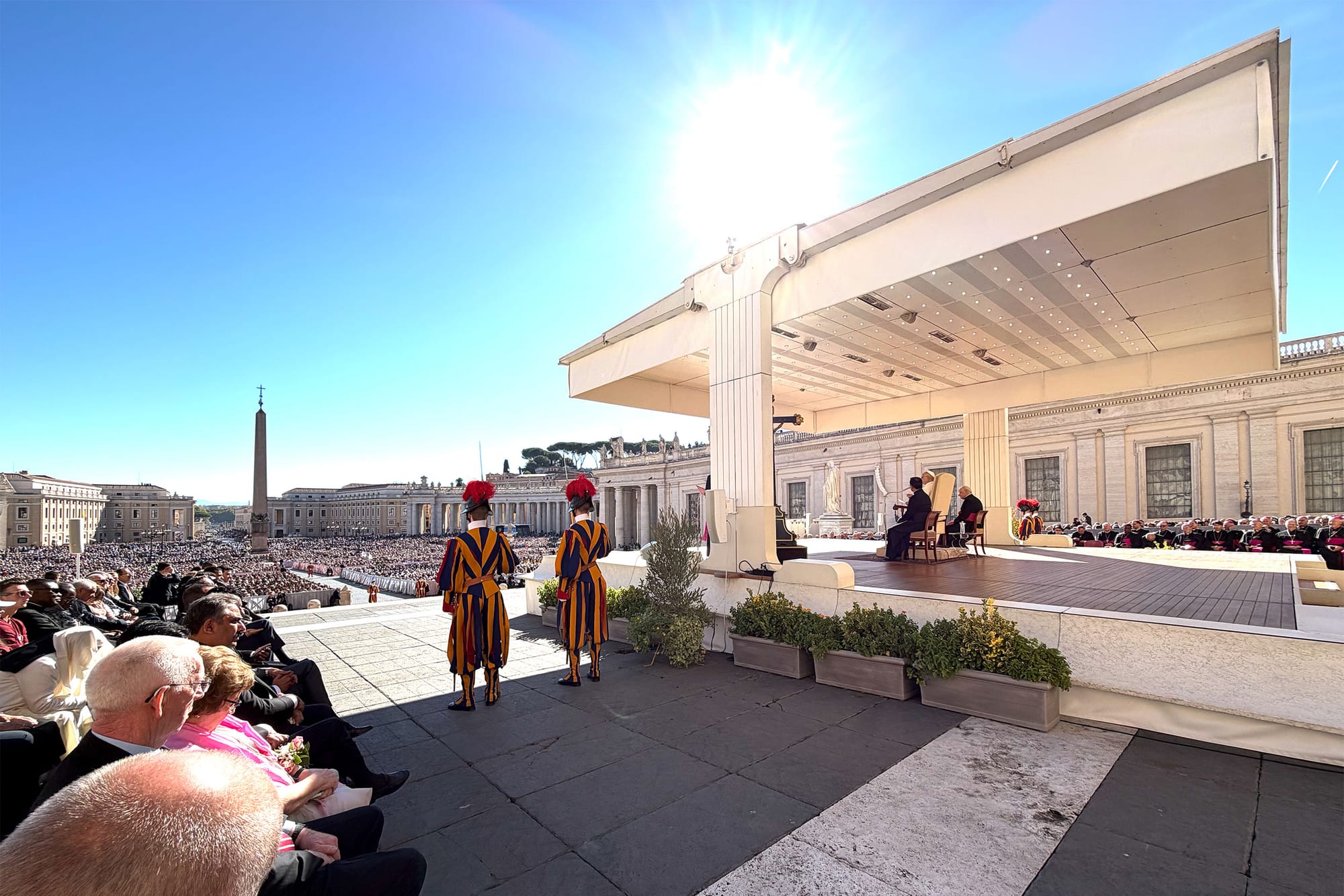 Pope Leo seated on a chair from the papal speaking platform overlooking Saint Peter's Square.