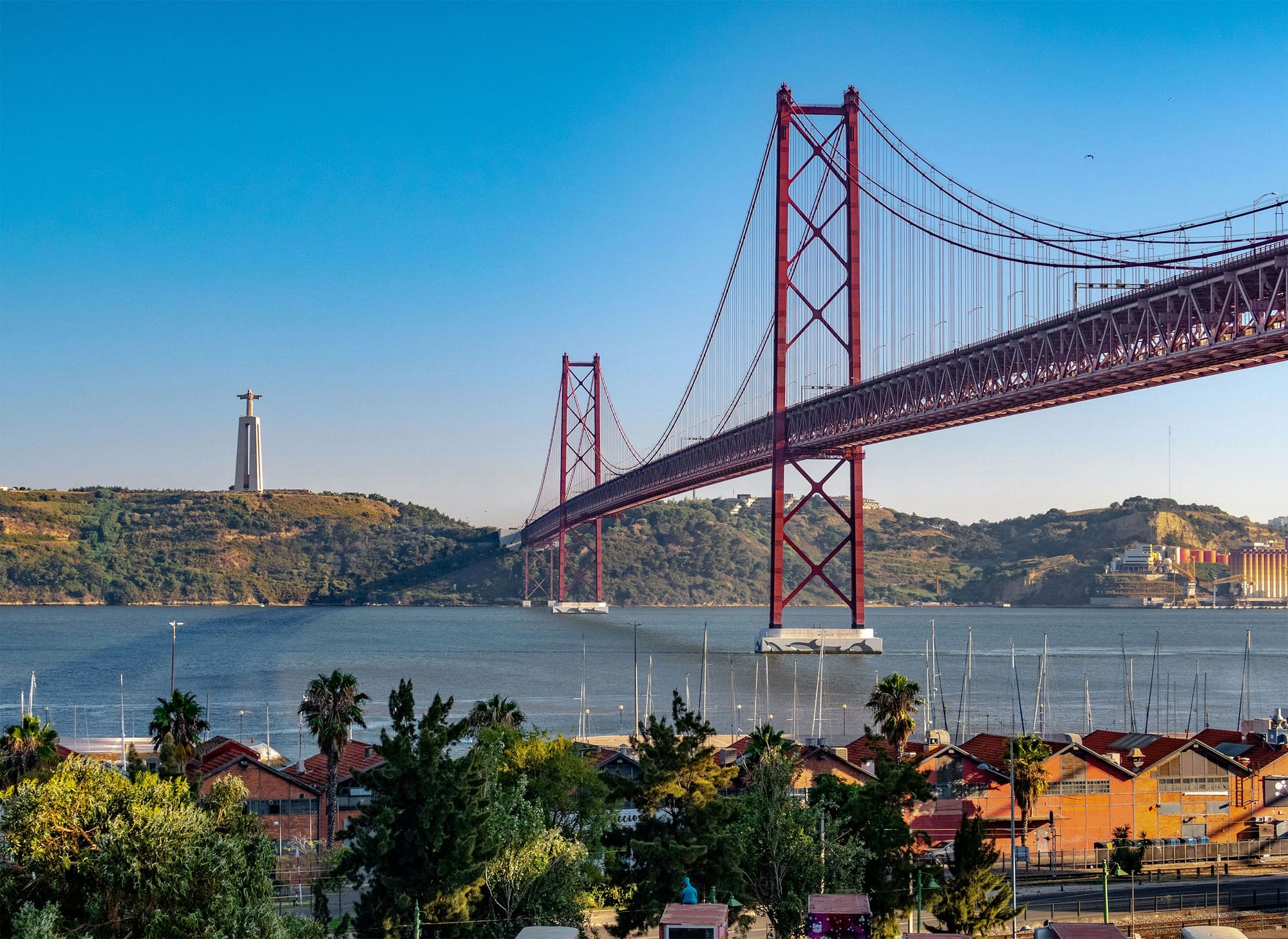 Statue of Christ the Redeemer on a hilltop opposite a bridge over the river.
