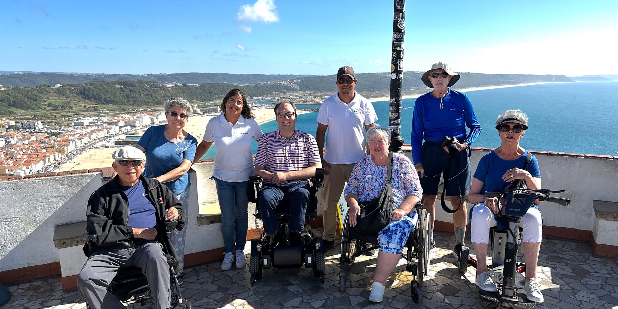 Group of wheelchair users overlooking a beach town in Portugal.