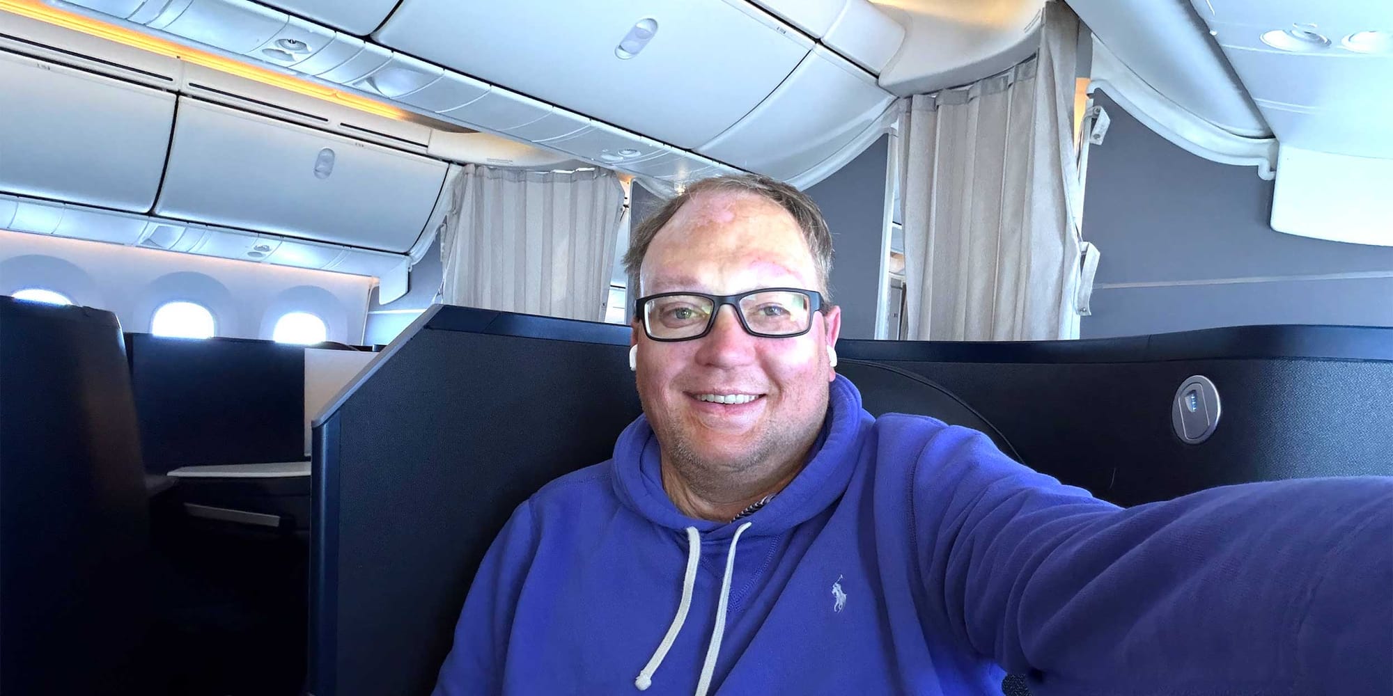 Selfie of John seated in business class seat.