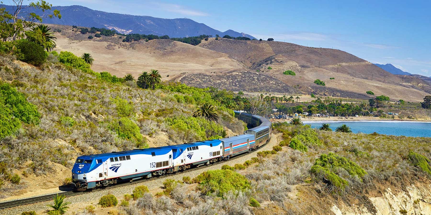 Amtrak train running along a rural hillside.