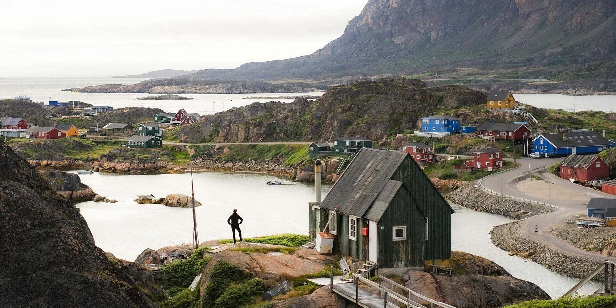 Houses spread across a rocky and hilly area in a Greenland village.
