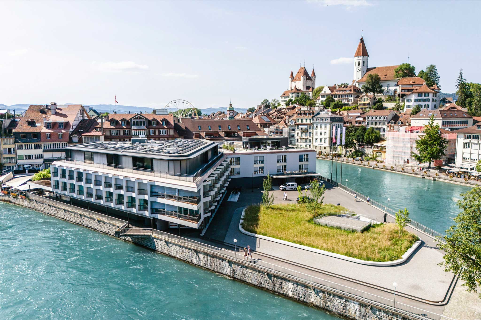 Exterior of hotel in Thun at intersection of waterways with a castle in the background.