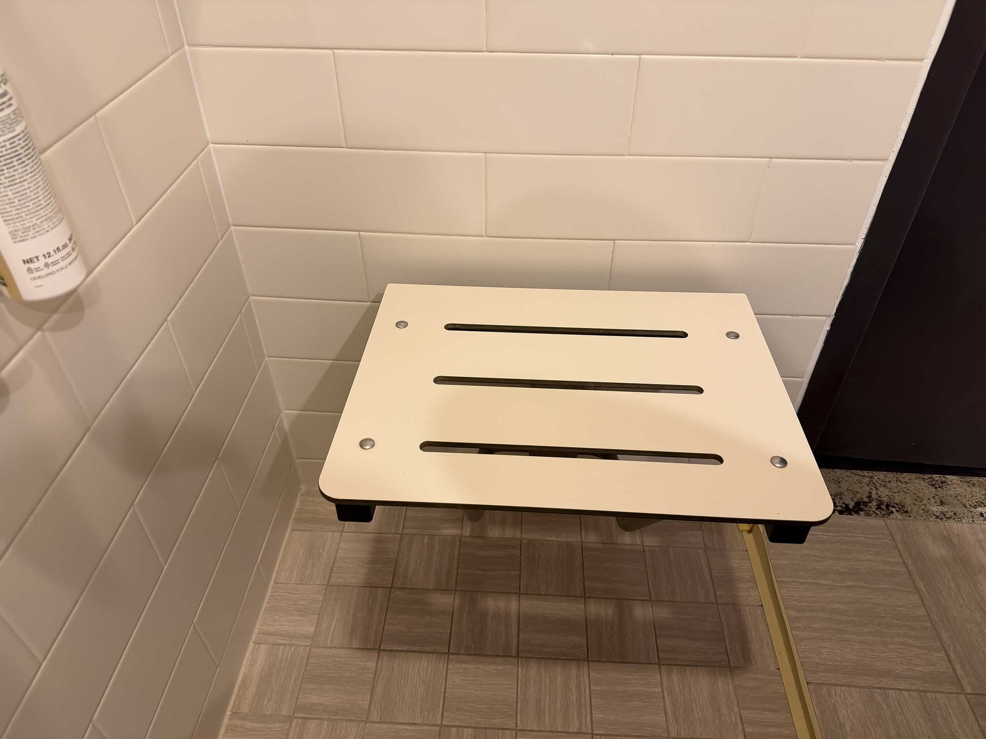 Wall-mounted seat in roll-in shower that sits 7 inches from the wall.