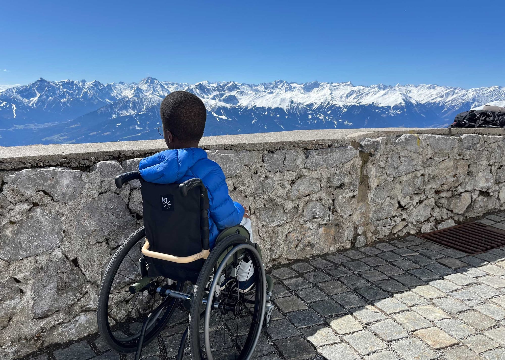 Robert seated in his wheelchair and looking towards snow-capped mountains from a viewpoint in Austria.