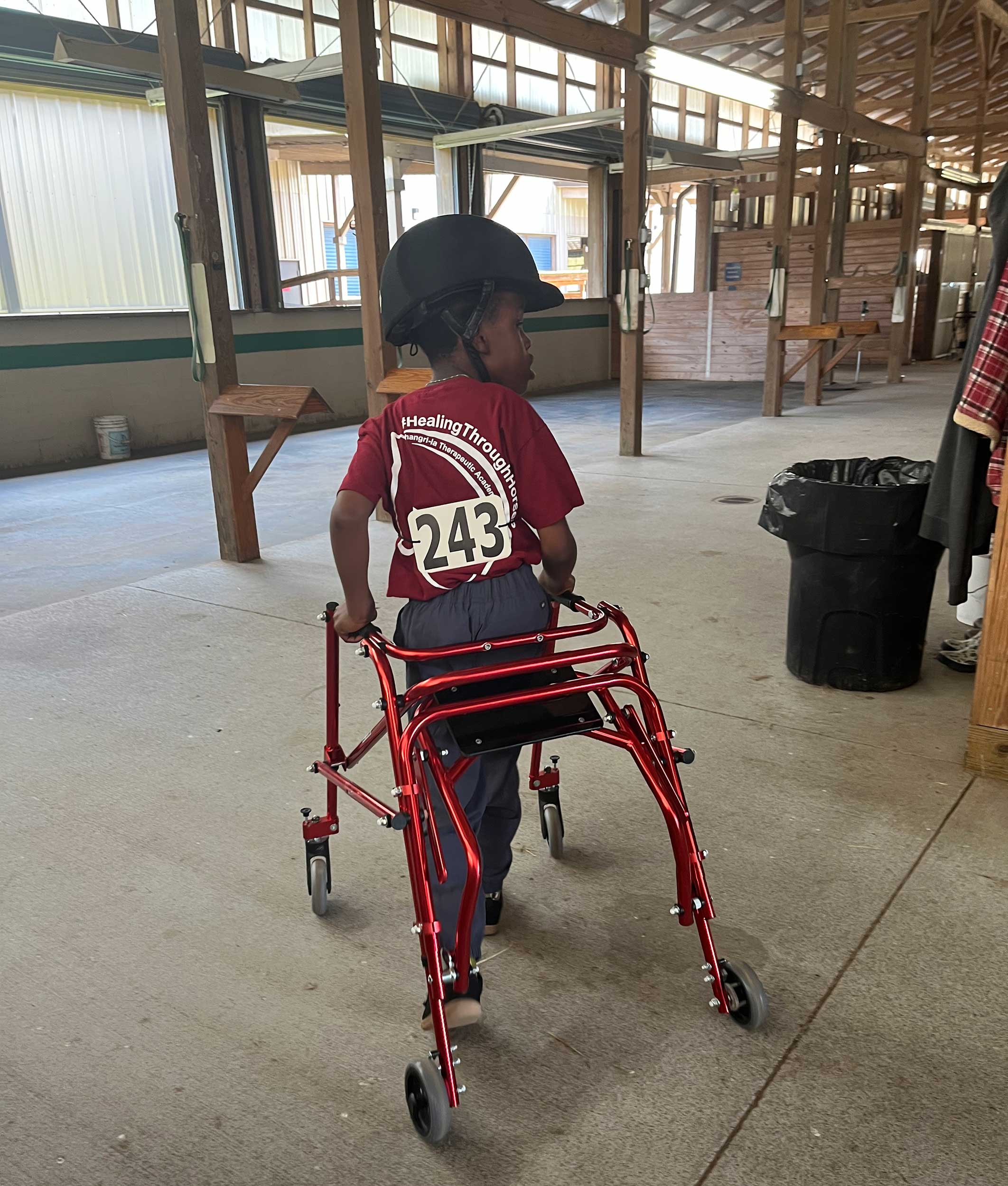 Robert using his walker in a horse barn.