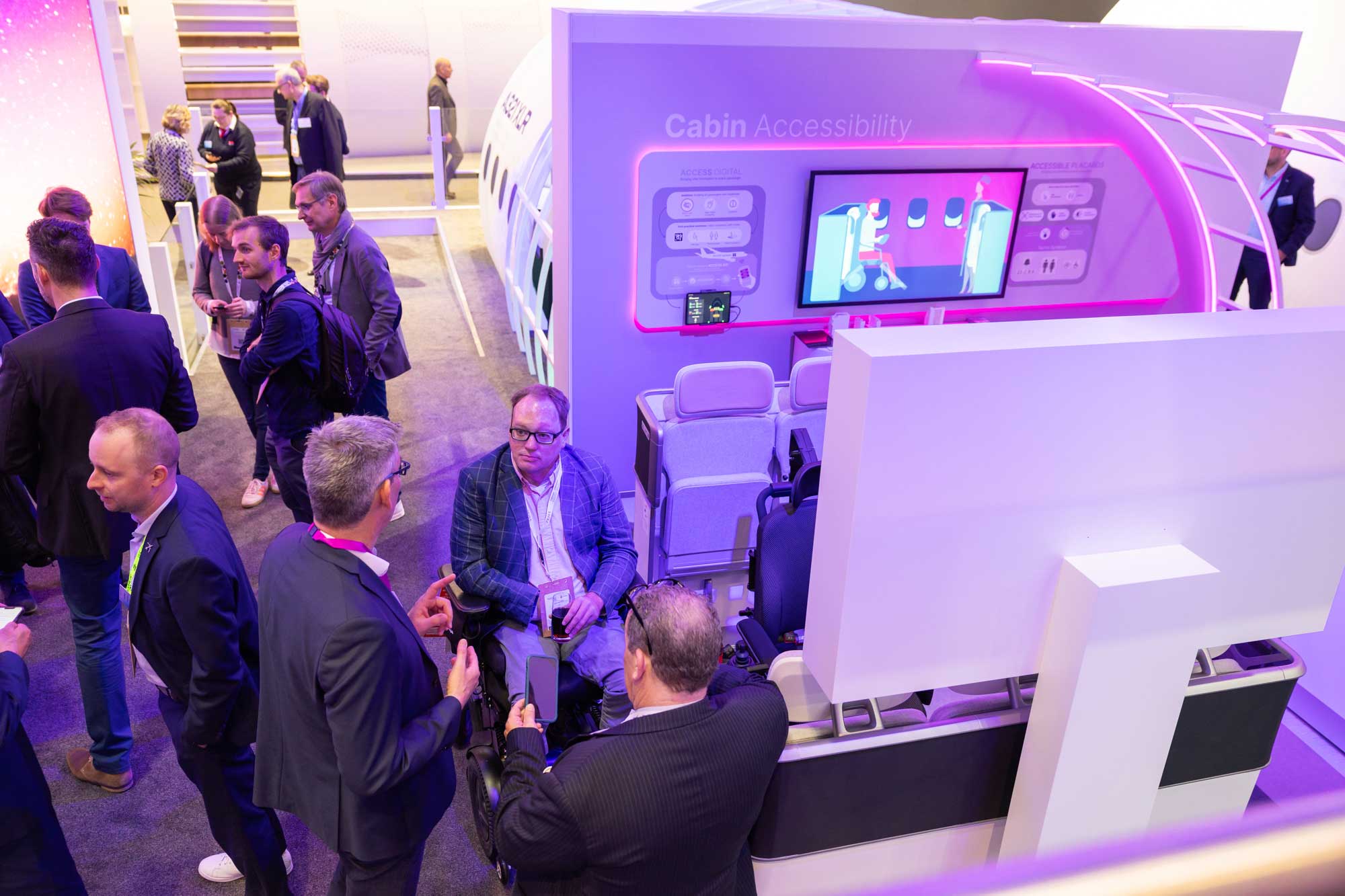 Overhead view of John speaking with Airbus team at accessibility display.
