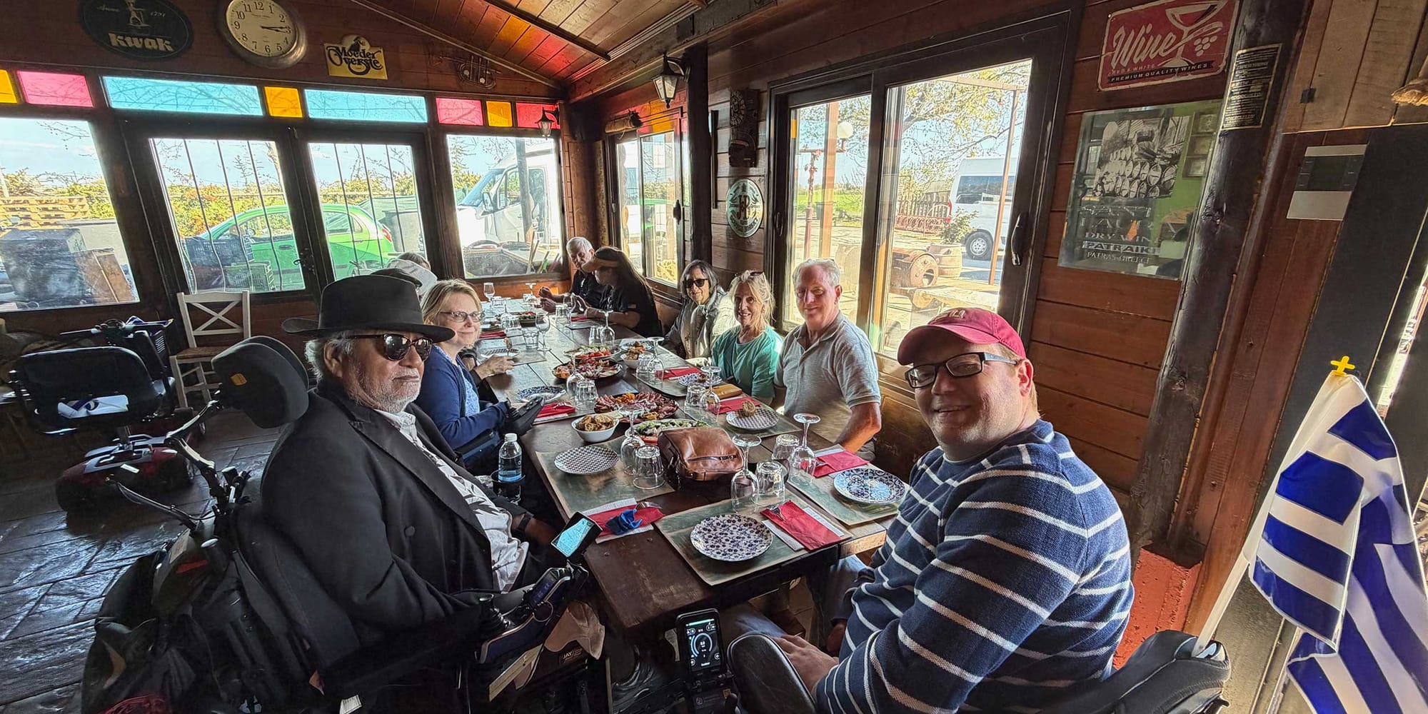 Wheelchair users seated around a table at a winery with glasses of wine and food.