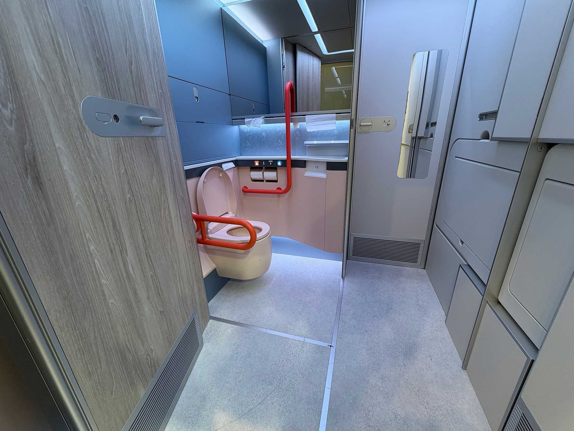 Spacious airplane lavatory with grab bars.