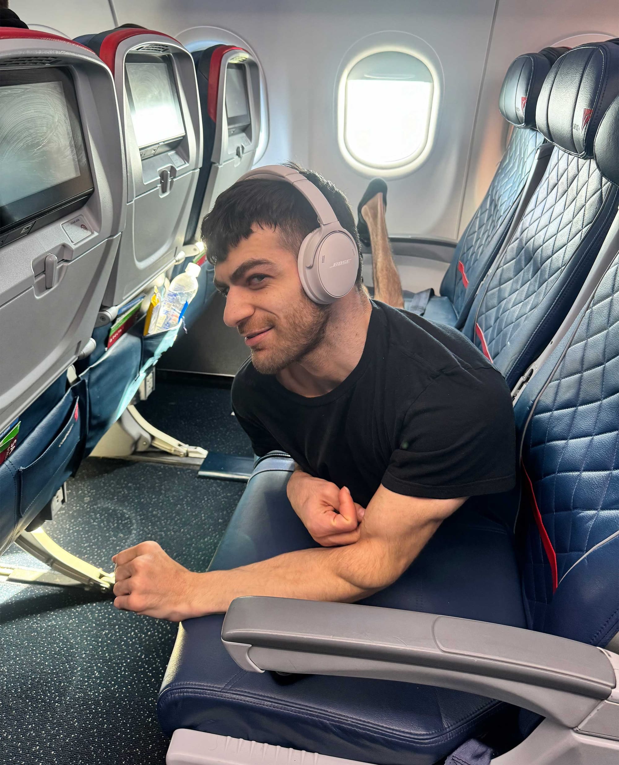Nolan seen laying down in a row of three airplane seats.