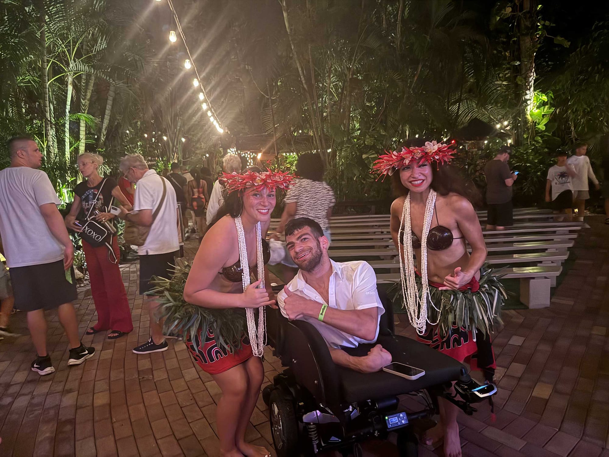 Nolan pictured with two dancers wearing flowers and hula skirts.