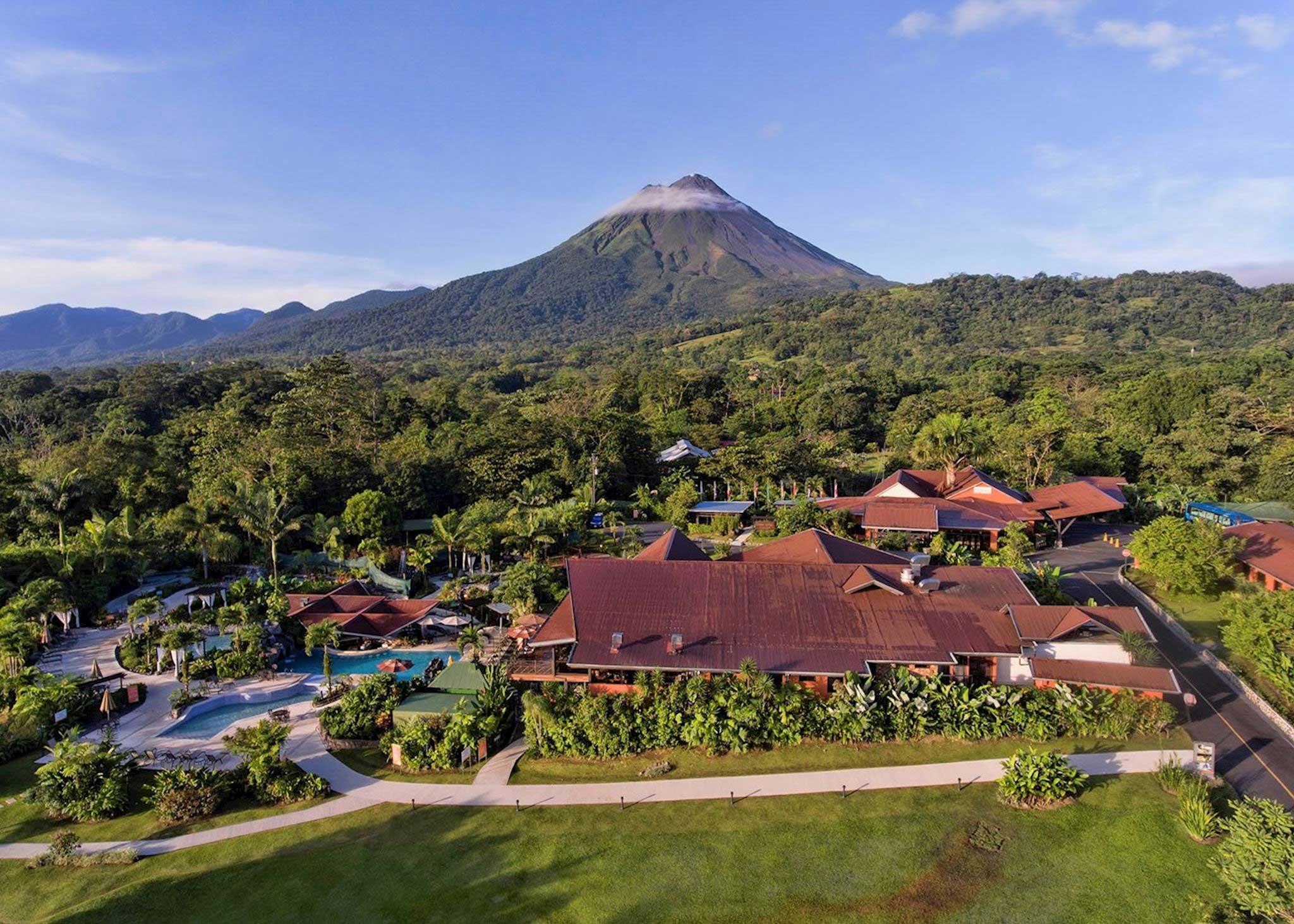 Hotel pictured at the foot of a volcano with lush vegetation.