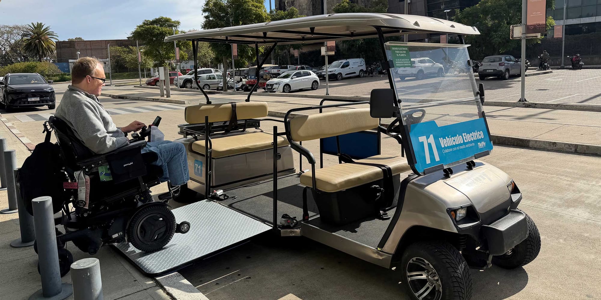 John rolling his power wheelchair onto a golf cart via a ramp.