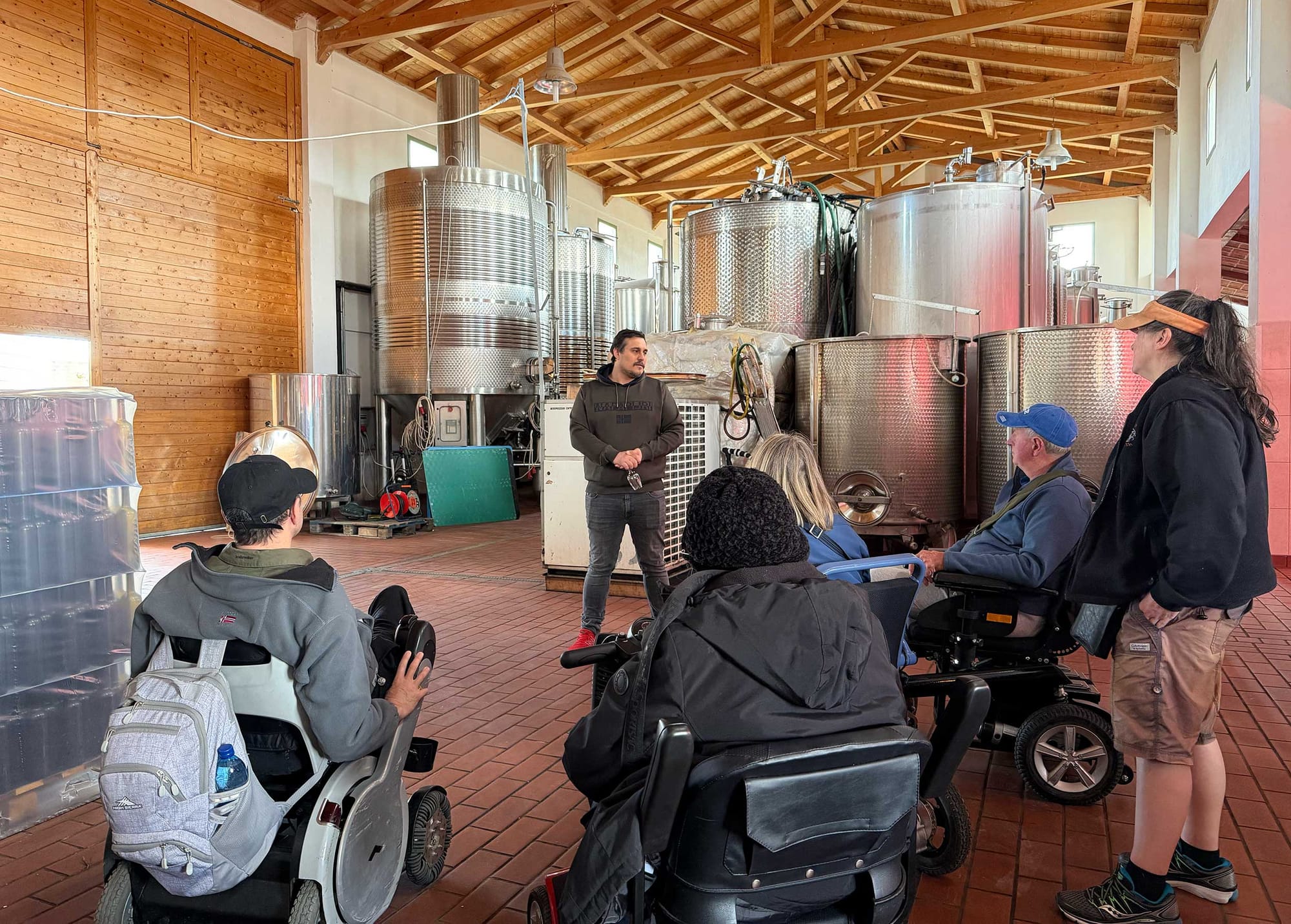 Group of wheelchair users inside a winery production facility.