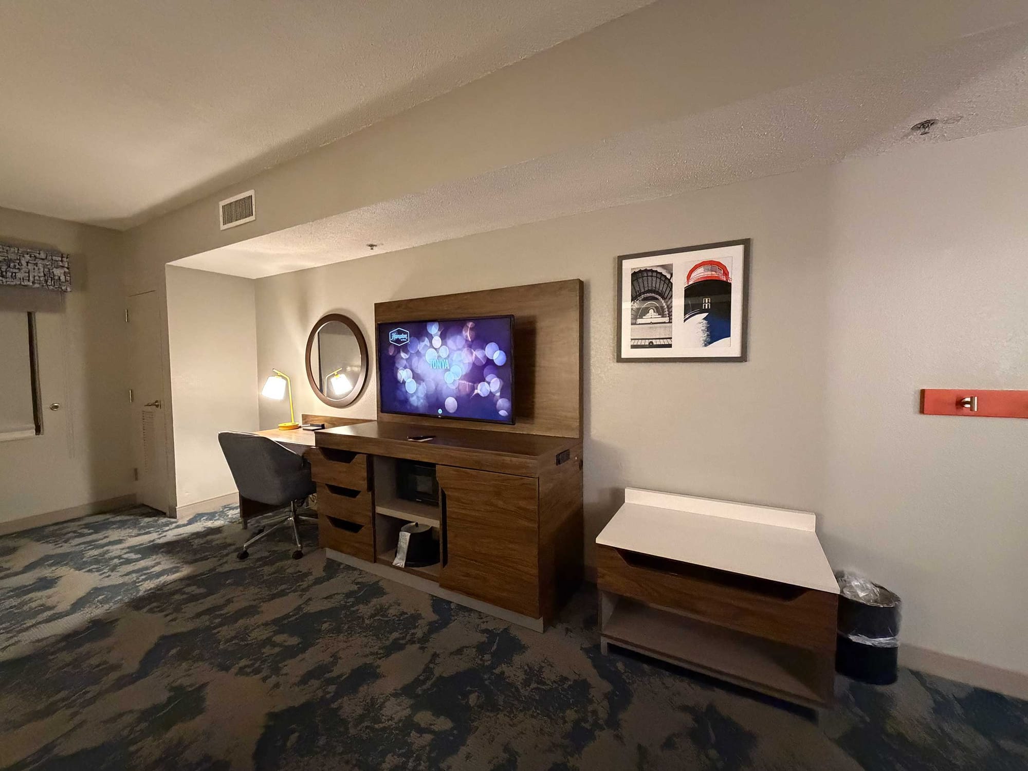 Desk area with office chair, wall-mounted television and dresser drawers.