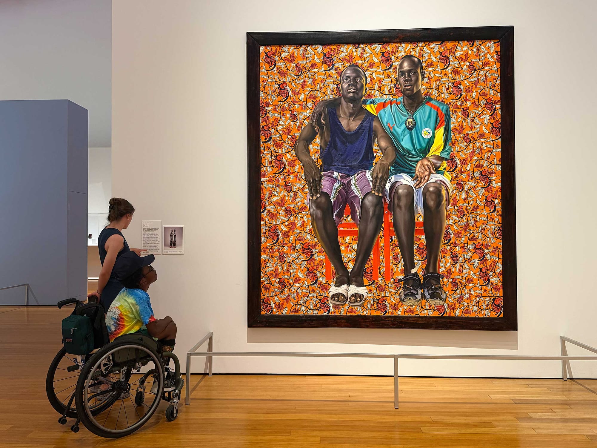 Stevie and Robert looking up at a larger than life painting of two young black men.