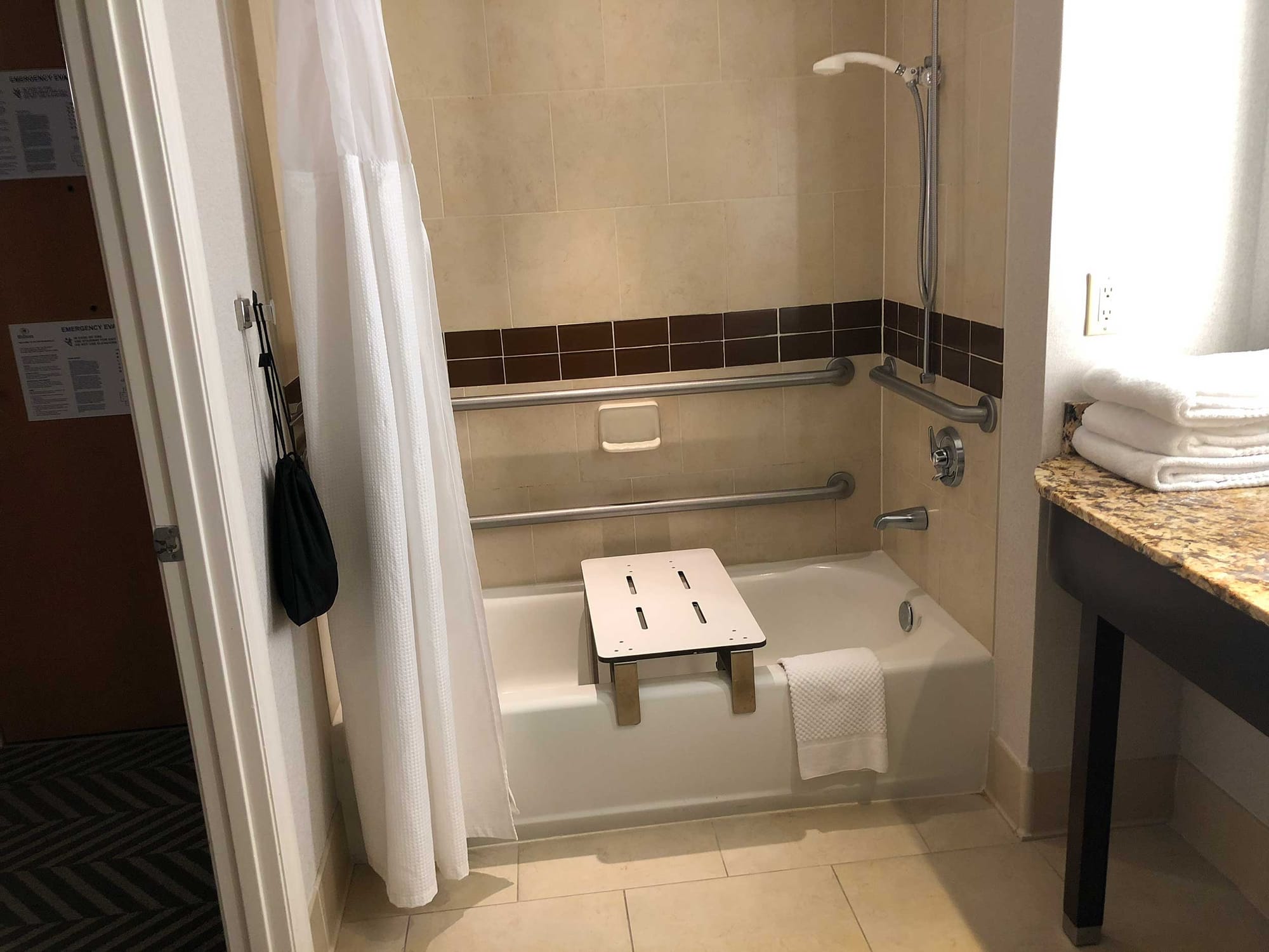 Accessible bathtub with a removable ADA-compliant seat installed spanning the tub width.