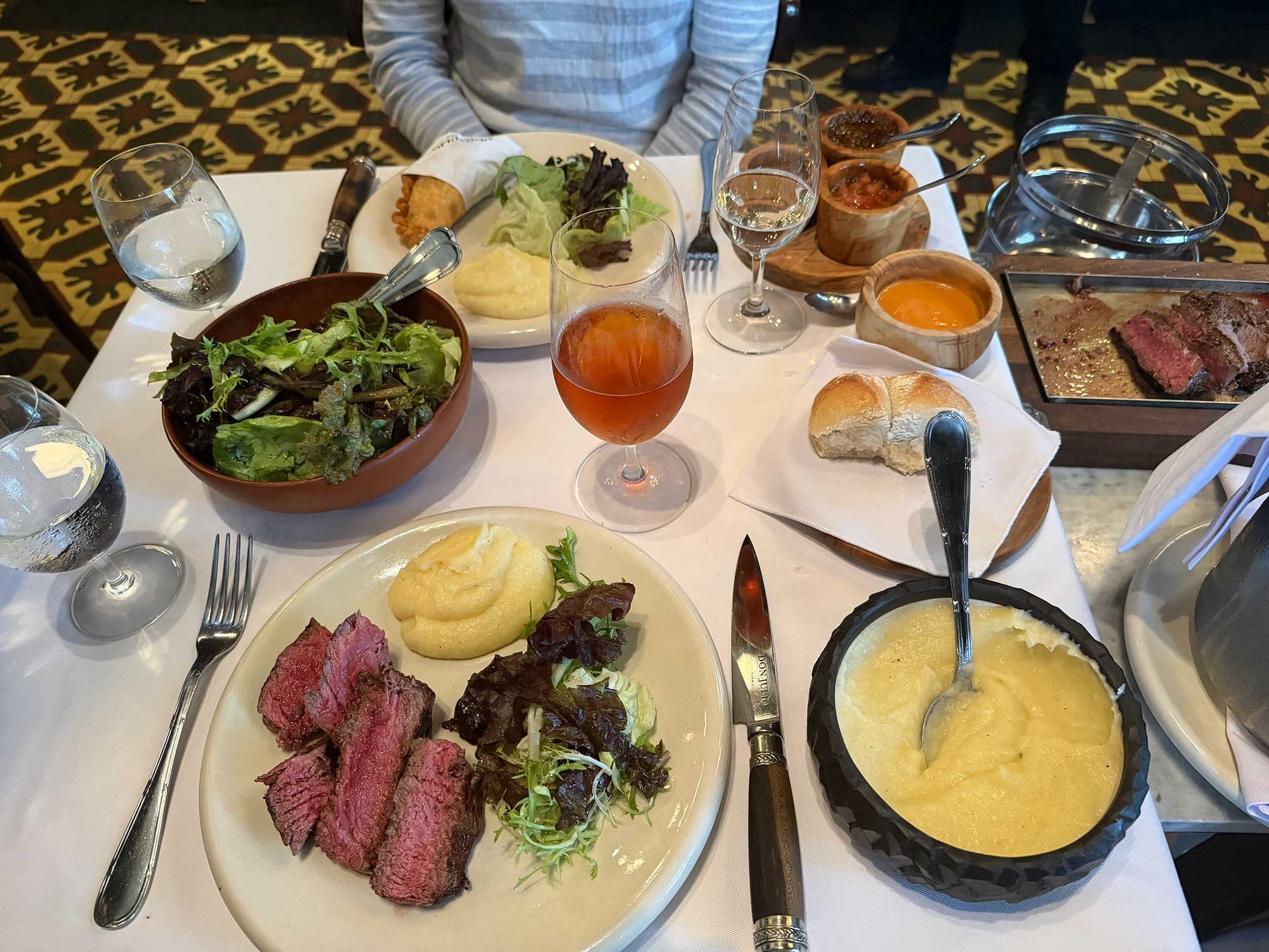 Steak, salad, mashed potatoes on table.