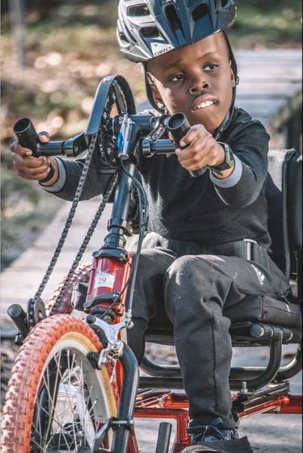 A young Robert using a wheelchair accessible bicycle.