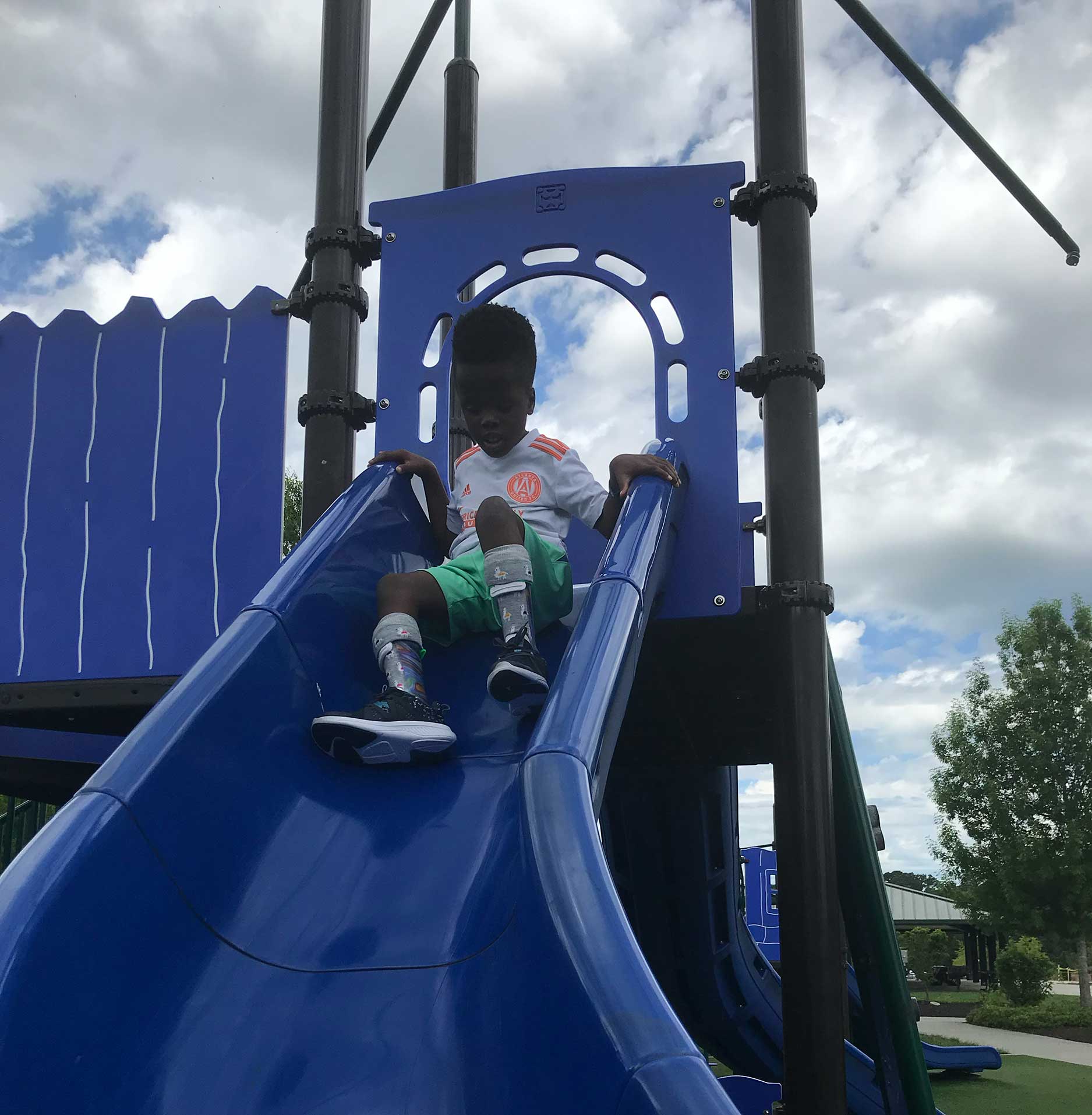 Robert on a slide in a playground.