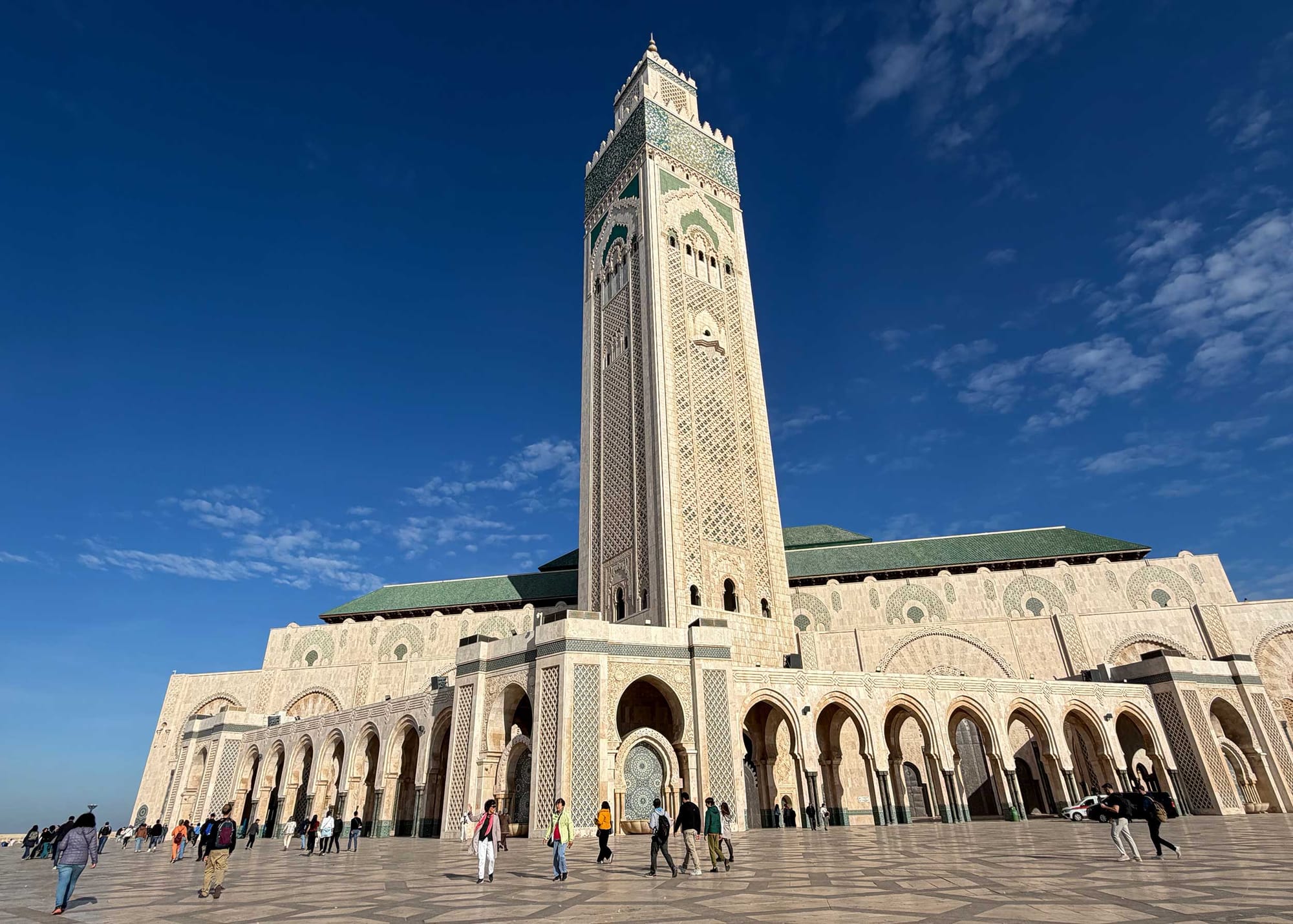 Exterior of a large mosque with a very tall tower minaret.