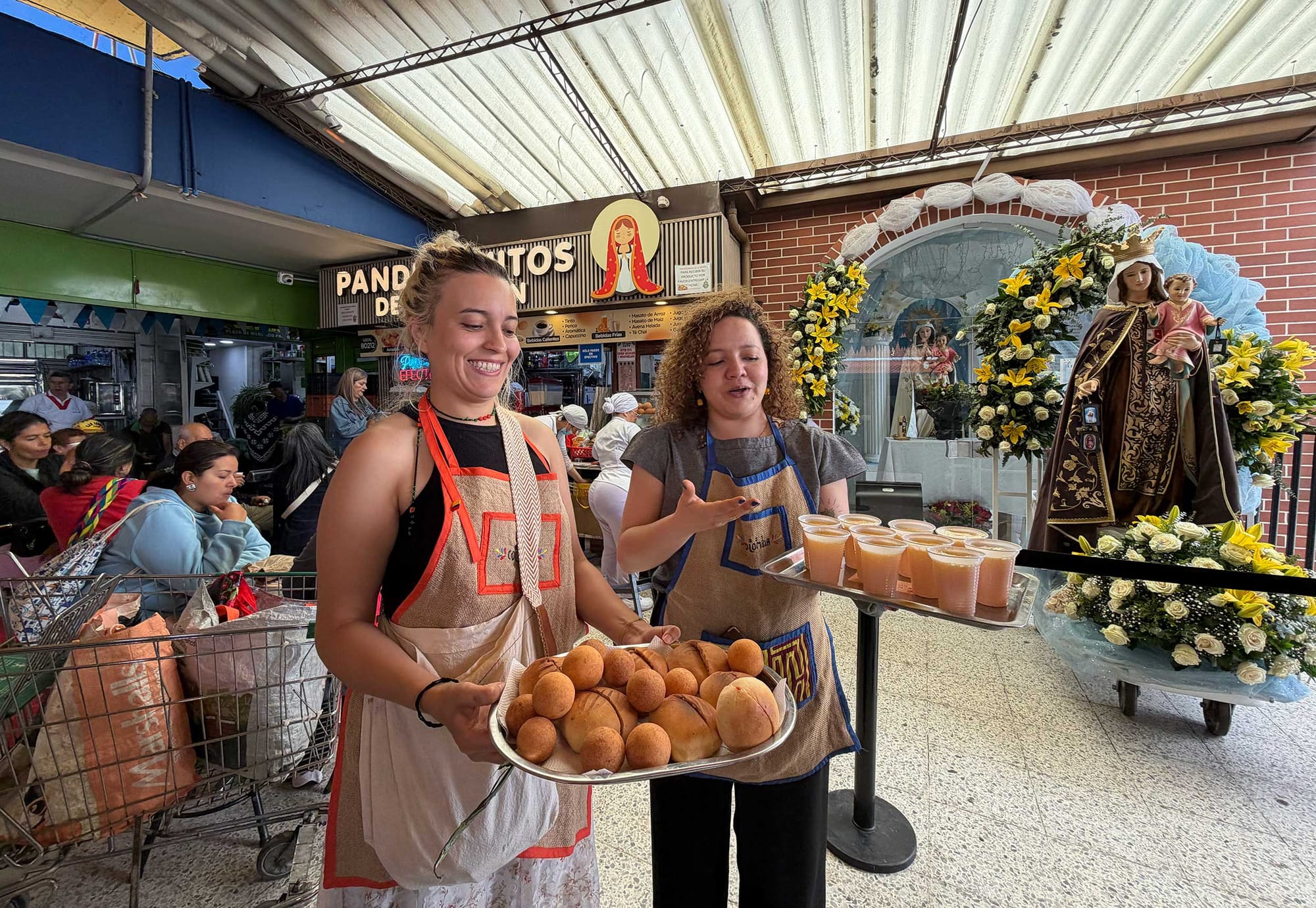 Two tour guides showcasing foods and drinks from the marketplace.