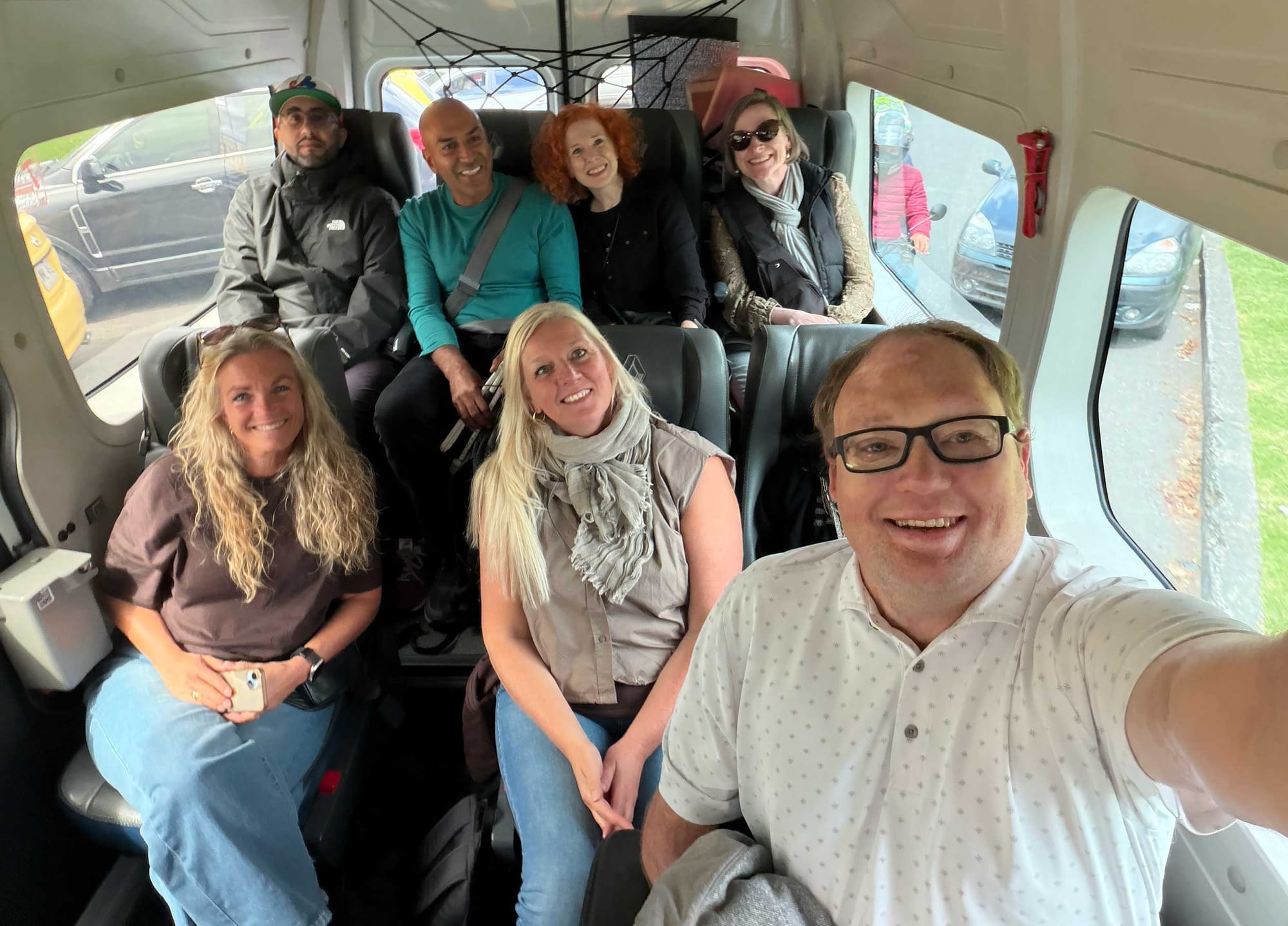 John taking a selfie with a group of people seated inside of a van.