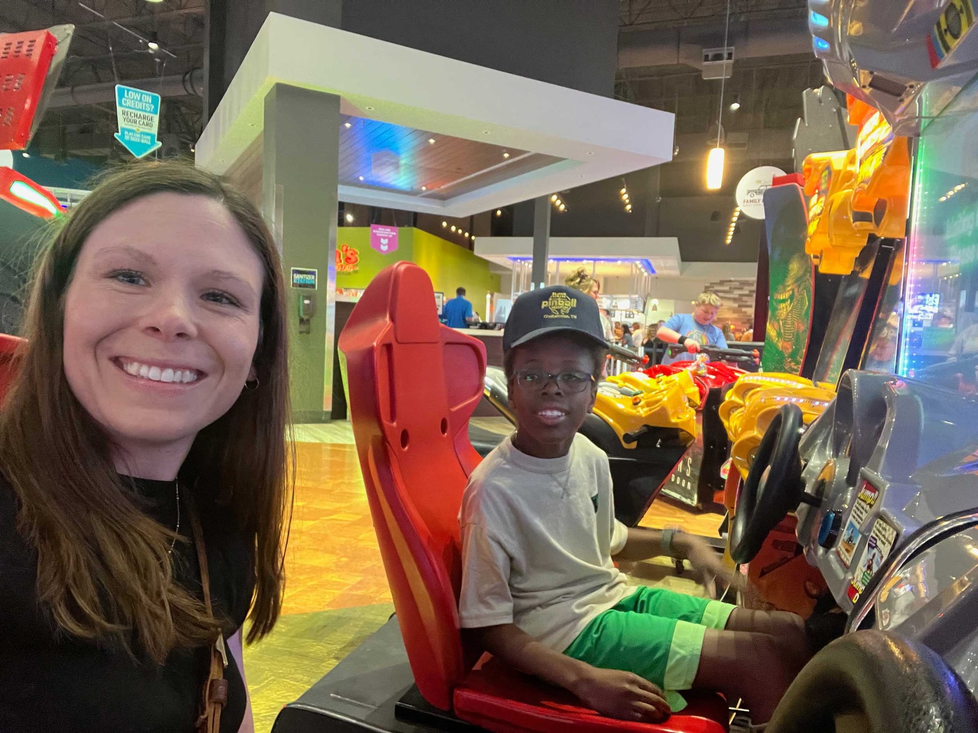 Stevie and Robert playing a car racing game at the arcade.