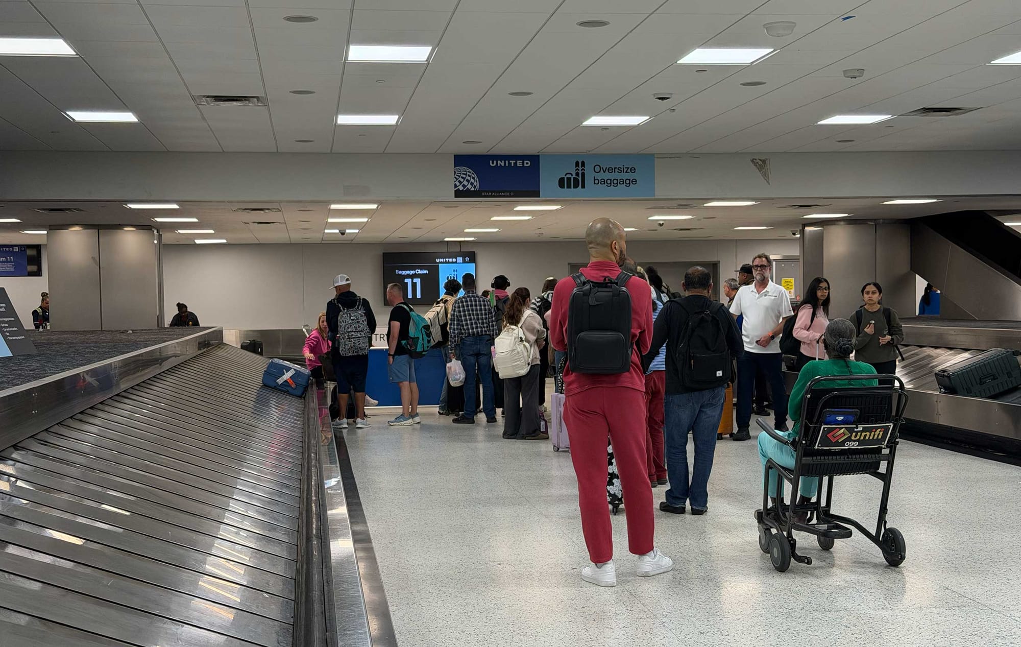 Line of people at the United baggage service stand at baggage claim.