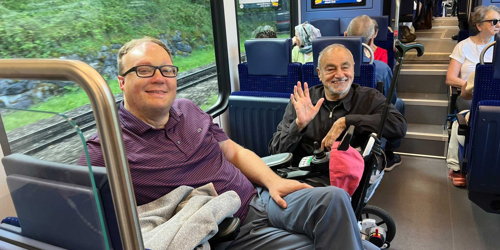John pictured sitting on a train with a fellow wheelchair user.