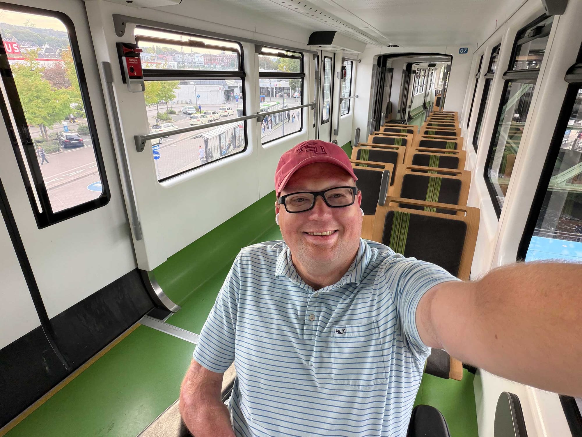 Selfie of John sitting in his wheelchair inside an empty Schwebebahn rail car.