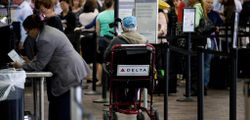 Older man seated in a wheelchair at the airport check-in area.