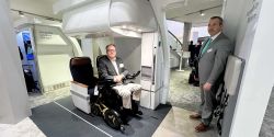 John seated in wheelchair securement seat prototype inside a mock airplane.