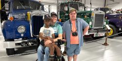 John and Robert with Houston from Downs and Towns posing in front of a series of Mack semi trucks.