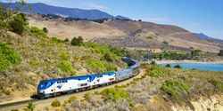 Amtrak train running along a rural hillside.