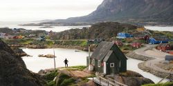 Houses spread across a rocky and hilly area in a Greenland village.