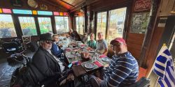 Wheelchair users seated around a table at a winery with glasses of wine and food.