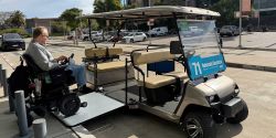 John rolling his power wheelchair onto a golf cart via a ramp.