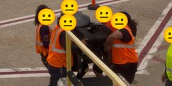 United Airlines baggage handlers manually carrying a power wheelchair.