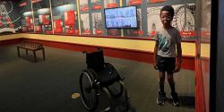 Robert standing next to his wheelchair inside a museum exhibit.