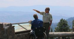 Park ranger speaking with a wheelchair user at an overlook inside a National Park.