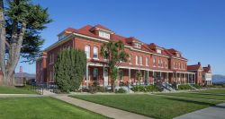 Exterior of The Lodge at the Presidio, a three story brick building sitting in front of the Golden Gate Bridge.