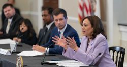 Kamala Harris speaking while seated at a table next to the Transportation Secretary.