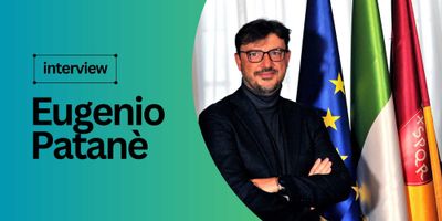 Official portrai of Eugenio Patane standing in front of European, Italian and City of Rome flags.