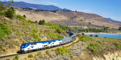 Amtrak train running along a rural hillside.
