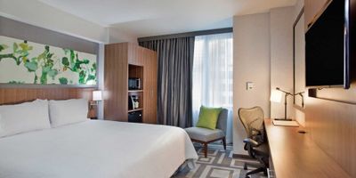 Hotel room with bed, desk, television, chair and more.